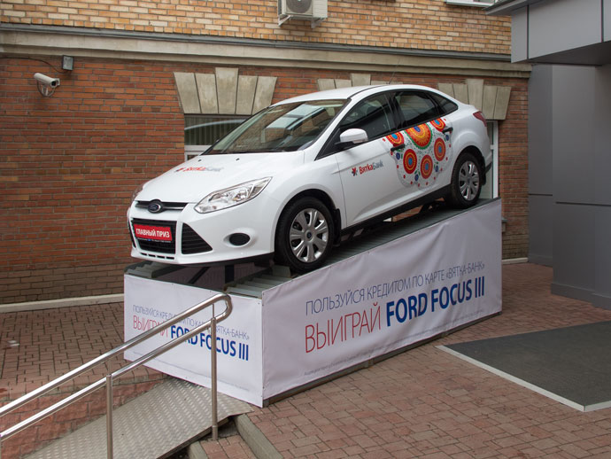 Новенький Ford со стильной дизайнерской окраской в цветах «Вятка-банка» стоит на постаменте около входа и ждет своего владельца